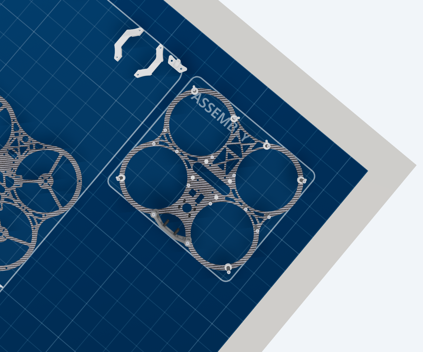 The bare bottom carbon plate on the assembly pad, its four ducted rotor rings empty, with the second plate still lying in the parts tray
